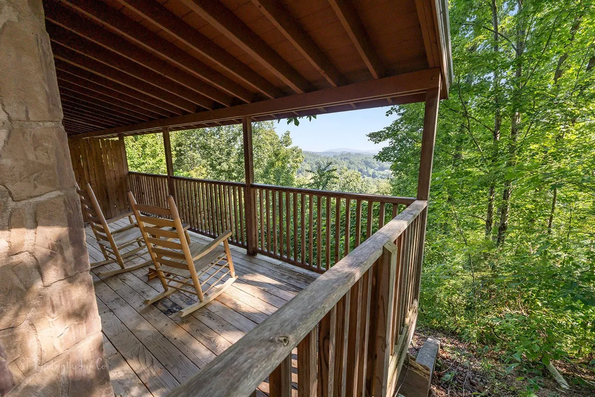 This shot offers a peaceful perspective from the porch, featuring comfortable rocking chairs, wooden railings, and a scenic mountain view framed by lush greenery. The inviting setting evokes quiet mornings before heading out or winding down in nature after a busy day of activities.
