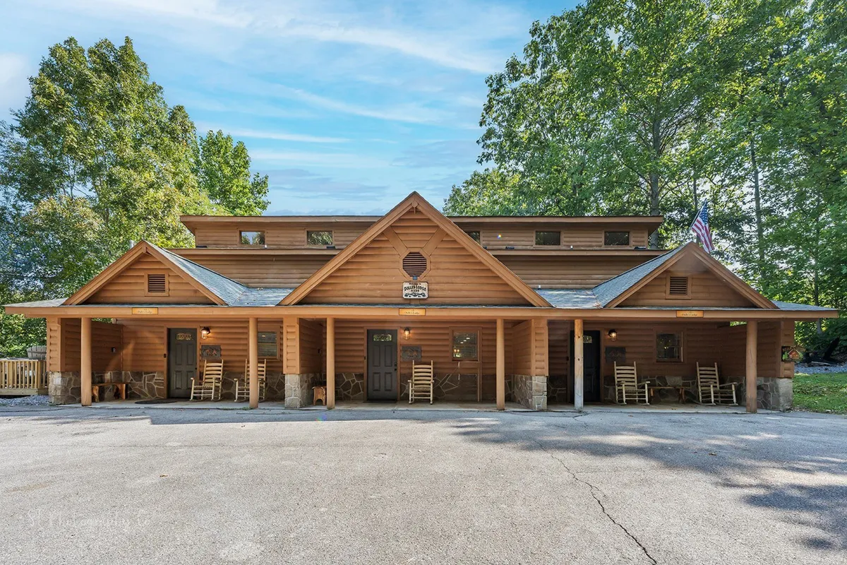 Another angle of the lodge’s exterior highlights traditional rocking chairs lining a spacious porch, framed by mature trees. The scene exudes warmth and togetherness, inviting families to relax after a day full of adventures or gather around for stories and marshmallows by the fire pit.